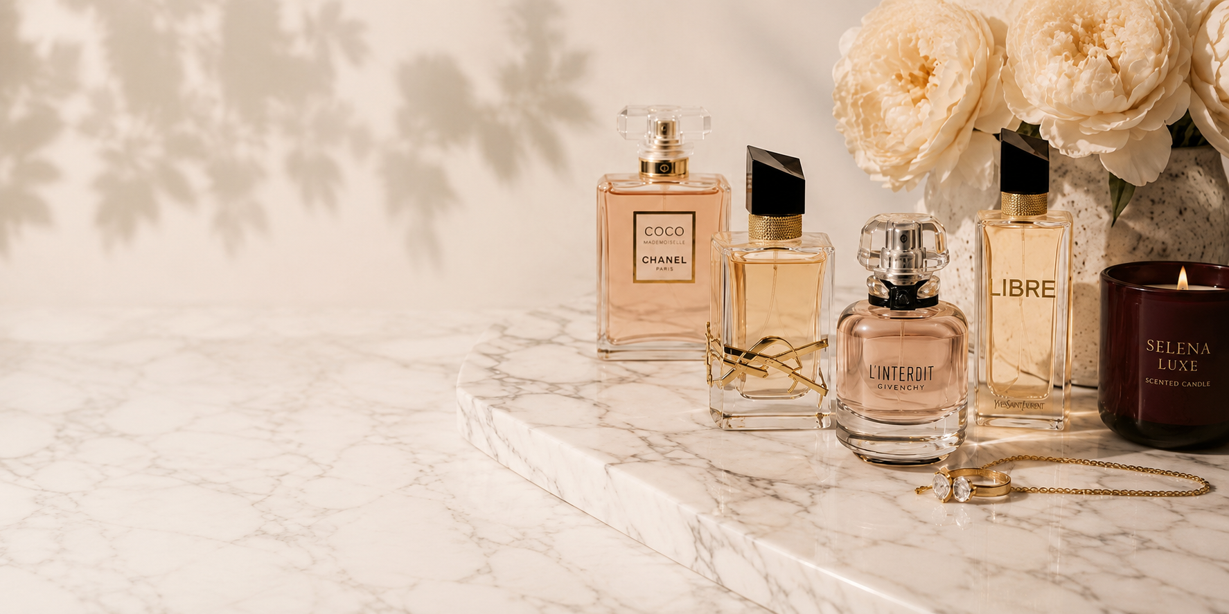 Collection of perfume bottles on a marble surface with flowers and candles.